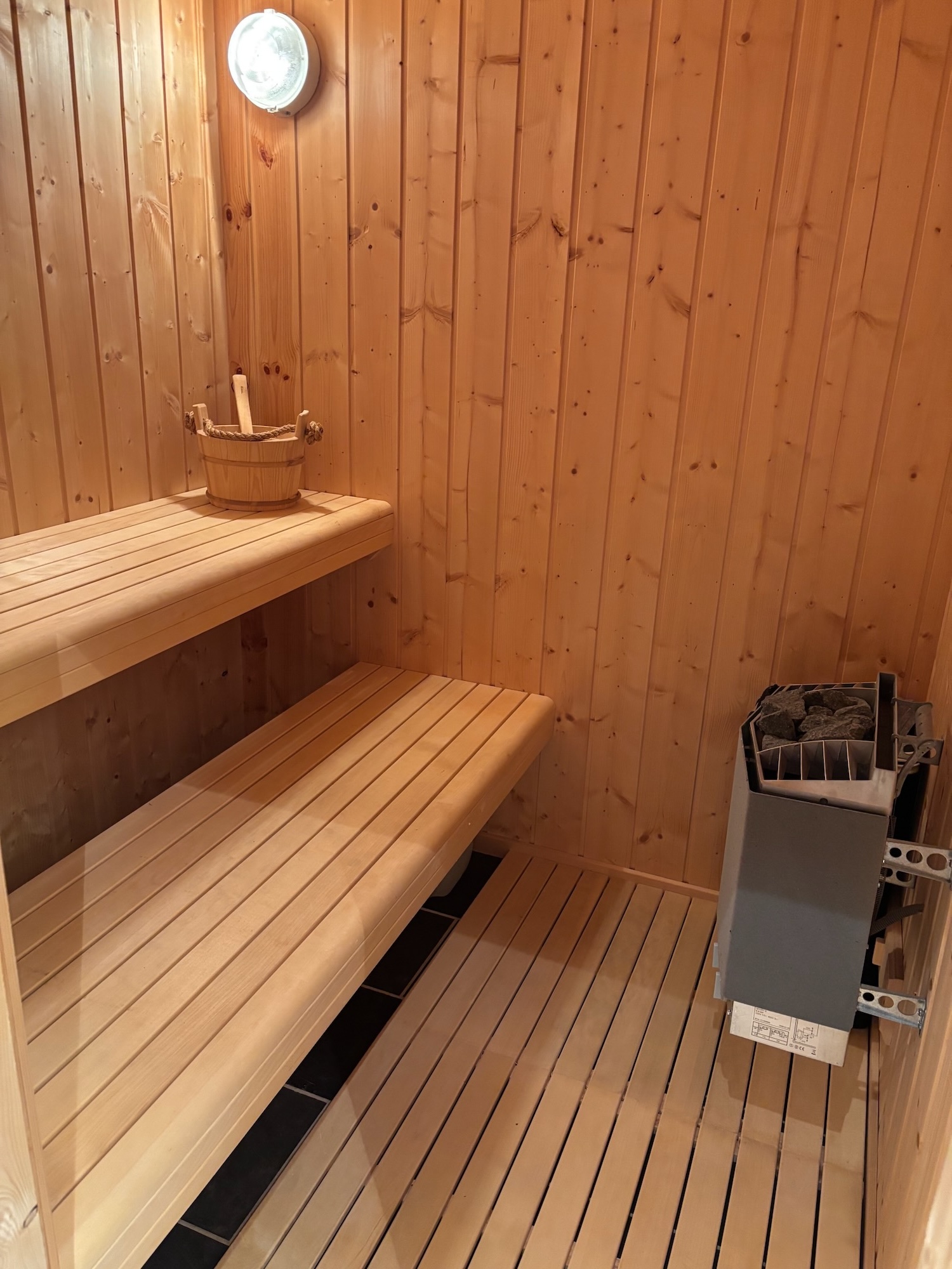 Traditional Finnish sauna with wooden benches and electric sauna heater.